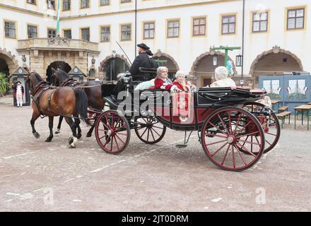 Gotha, Germany. 27th Aug, 2022. Performers in historical costumes ride in a horse-drawn carriage in the courtyard of the residential palace at the 20th Gotha Baroque Festival. Friedenstein Palace will once again be transformed into the colorful residence of Duke Friedrich III of Saxony-Gotha-Altenburg (r. 1732-1772). Credit: Bodo Schackow/dpa/Alamy Live News Stock Photo