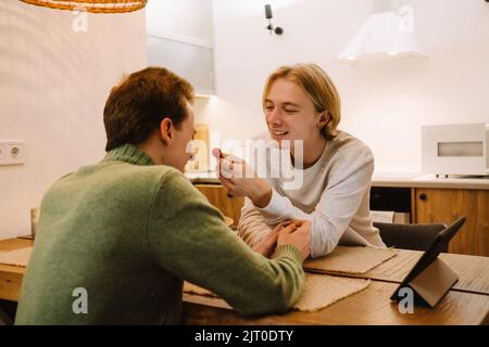 European gay couple smiling and using tablet computer together at home Stock Photo