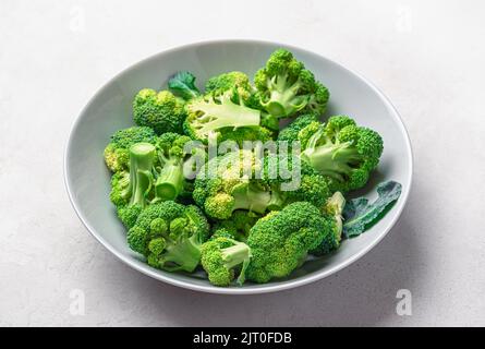 Broccoli in a plate on a gray wooden background. Cooking broccoli. Stock Photo