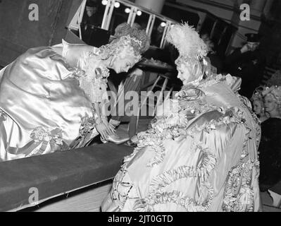 Female / Girl Extras having trouble putting their shoes on due to their Hoop Skirts on set candid during filming of MARIE ANTOINETTE 1938 director W.S. VAN DYKE art direction Cedric Gibbons gowns by Gilbert Adrian producer Hunt Stromberg Metro Goldwyn Mayer Stock Photo