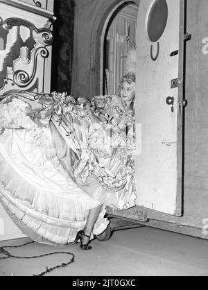 Female / Girl Extra has trouble with her Hoop Dress at Dressing Room door on set candid during filming of MARIE ANTOINETTE 1938 director W.S. VAN DYKE art direction Cedric Gibbons gowns by Gilbert Adrian producer Hunt Stromberg Metro Goldwyn Mayer Stock Photo