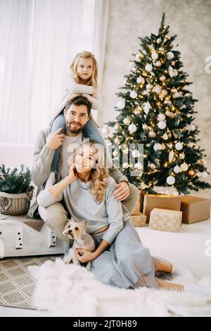 Happy family: mom, dad and pet. Family in a bright New Year's interior with a Christmas tree. Stock Photo