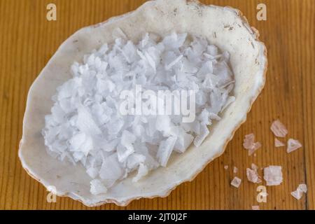 Salt crystals in sea shell on wood table, natural organic salt photo Stock Photo