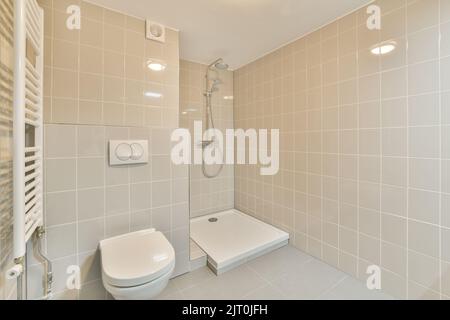 Stylish bathroom interior design with white toilet and bathtub with glass shower in modern apartment Stock Photo