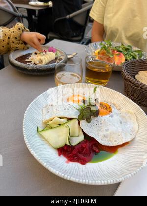 Fried eggs with greens on a plate on the table Stock Photo