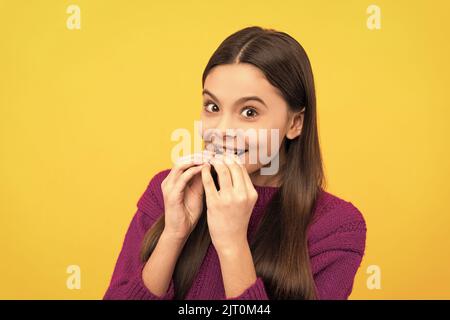 Happy kid sweet-tooth enjoy eating tasty chocolate slab yellow background, snack Stock Photo