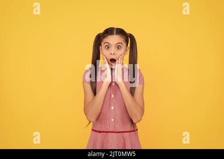 Kind of shocked. Kid got shocked. Surprised girl yellow background. Shock and surprise Stock Photo