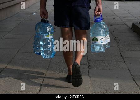 A man is seen carryin large plastic bottle of water in Warsaw, Poland on 26 August, 2022. Stock Photo
