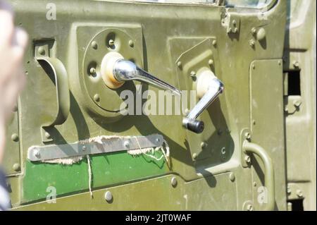 Bright interior door of a vintage car waiting to be restored. A vintage window opener on the inside of the door. In green colors close up Stock Photo