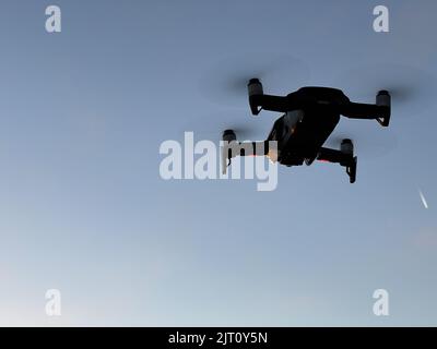 Drone hovering in the air against the blue sky Stock Photo
