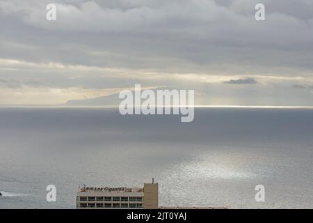 View of sunrays through the clouds over La Gomera Island from Los Gigantes, Tenerife, Canary Islands, Spain. Stock Photo