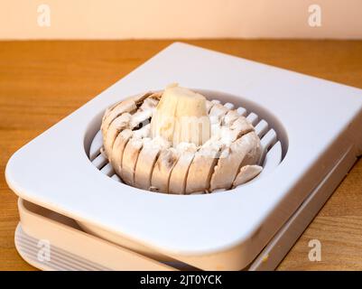 a closed cup mushroom in an  Egg slicer on wooden background Stock Photo