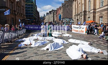 Royal Mile, Edinburgh, Scotland, UK. 27th August 2022. Edinburgh's Extinction Rebellion members protest the ongoing climate crisis in a “die-in” protest by lying outside St Giles Cathedral covered in white sheets, next to placards highlighting the causes of climate-related deaths. Credit: Arch White/alamy live news Stock Photo