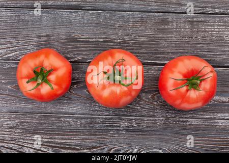 three tomatoes on wood background Stock Photo