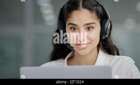 Close-up young woman assistant sales agent advisor hotline consultant answering incoming call using headset looking at laptop screen talking to client Stock Photo