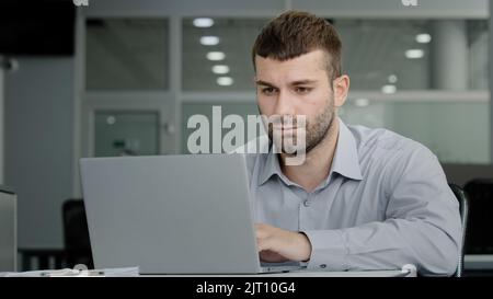 Serious focused executive businessman working on laptop communicating with colleague via video call discussing work plan professional office manager Stock Photo