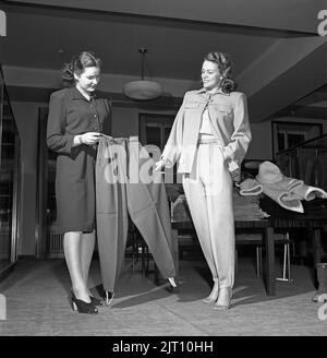 Shopping in the 1940s. A young woman in a store where a sales woman is presenting some of the stores selection of winter trousers, typically a fashion of the 1940s in a syntethic material with straps under the feets, often used when skiing but also the every day fashion of the young. Sweden 1947. Kristoffersson ref Y71-3 Stock Photo