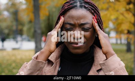 Close-up unhealthy frustrated woman holding head suffering from headache feels burning pain squeezing pressure suffers from chronic migraine unhappy Stock Photo