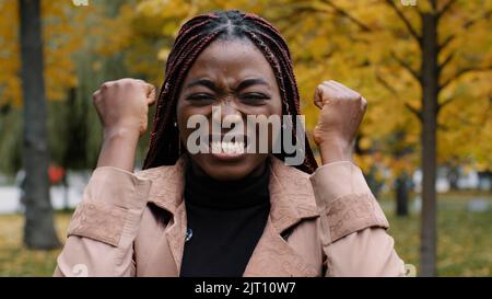 Close-up worried anxious young woman standing outdoors shouting loudly in rage covers ears with palms from noise annoyed frustrated girl feels stress Stock Photo
