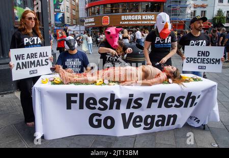 London, UK. 27th Aug, 2022. Peta protest in Leicester Square World Day for the End of Speciesism (27 August), when a trio of protesters dressed as animals dine on” a “blood-smeared” human in London's Leicester Square. The “lunch-in” is part of PETA's efforts to challenge speciesism - the belief that the differences between humans and other animals are enough to warrant torturing, killing, and eating those of a different species to us. Credit: Karl Black/Alamy Live News Stock Photo