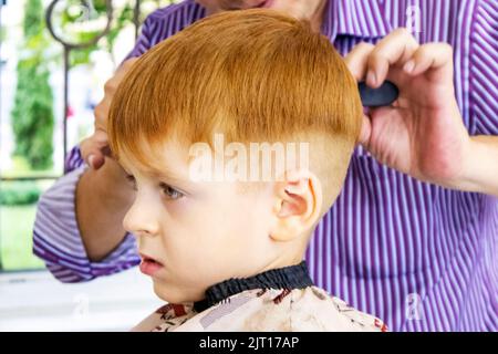 haircut of a little red-haired boy. beauty salon. kid's barbershop Stock Photo
