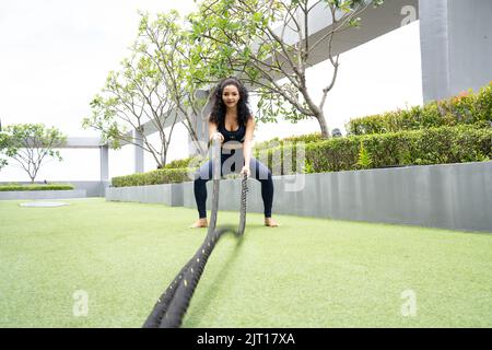 Woman doing Battle rope workout on roof top Condominium Stock Photo