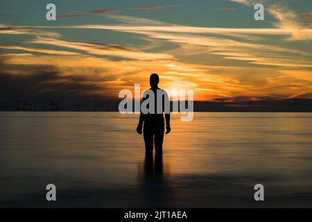 Sunset with an Iron Man seen on Crosby beach near Liverpool, taken 22nd Aug 2022. Stock Photo