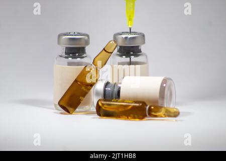 Empty medicine ampoules, vials and needles used for medical treatment, isolated white background, selective focus, noise effect Stock Photo