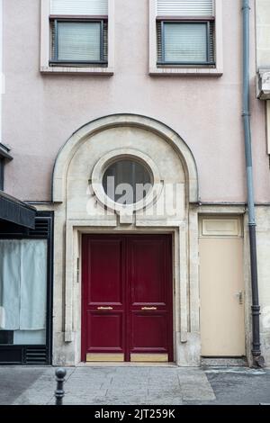 Close-up of a vintage red front door of a building in Paris, with a stone arch above Stock Photo