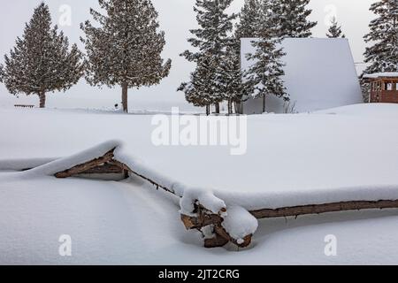 An A-Frame structure on Manitoulin Island with a foreground split-rail fence almost completely covered in snow. Stock Photo