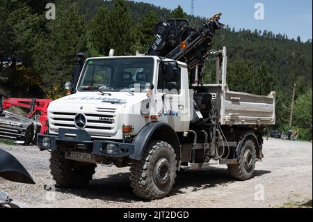 A white Mercedes Benz Unimog G5000 off-road truck with a crane parked on a construction site Stock Photo