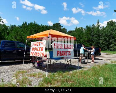 Woman and girl selling from a fresh hot boiled peanut stand, to a customer as a roadside business in Montgomery Alabama, USA. Stock Photo