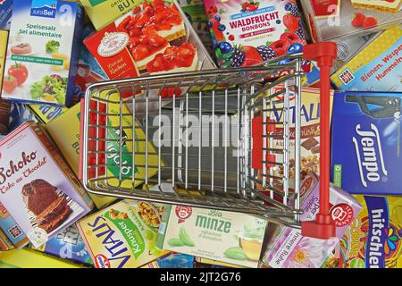 Viersen, Germany - July 9. 2022: Top view on one isolated empty shopping cart model between expensive branded products Stock Photo