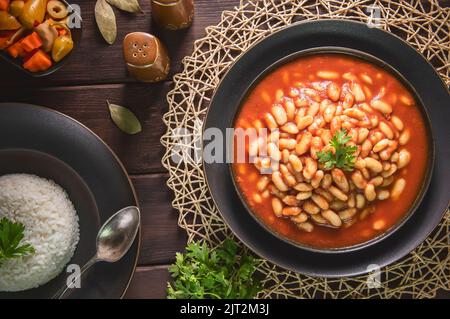Arabic Cuisine; Middle Eastern traditional white beans in tomato sauce. Served with white rice and oriental pickles. Stock Photo