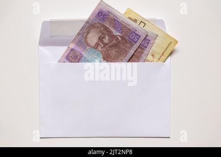 Ukrainian 50 and 100 UAH lie in a white envelope on a white background, financial background, hryvnia Ukraine Stock Photo