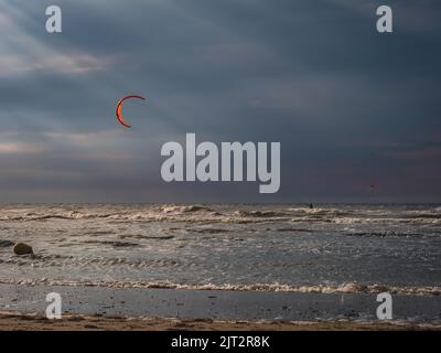 Kite surfer heading towards sun rays prior to sunset Stock Photo
