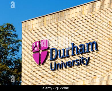 Durham University shield or logo on sign on sunlit brick wall. County Durham Uk Stock Photo