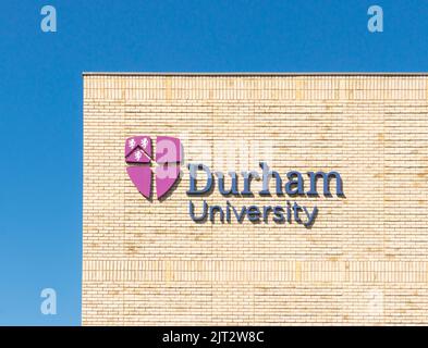 Durham University shield or logo on sign on sunlit brick wall. County Durham Uk Stock Photo