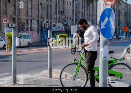 Black man rides green bicycle in the city of Tel Aviv. Stock Photo