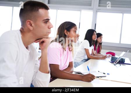 University student listening lecture while attending a class in the classroom.  Stock Photo