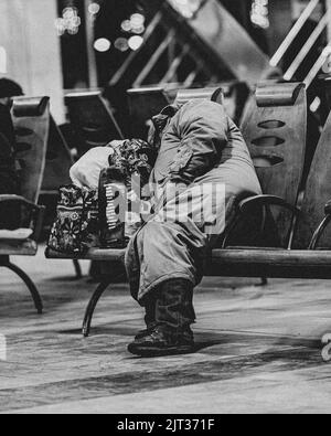 A grayscale closeup shot of homeless person sleeping at the station Stock Photo