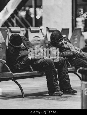 A closeup grayscale shot of sleeping homeless men in the station Stock Photo