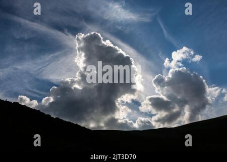 Huge dramatical clouds in the mountains before sunset. Cumulus clouds on the background of the blue sky Stock Photo