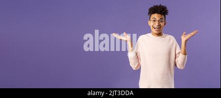 So what, I wear glasses. Portrait of unbothered, happy optimistic guy with dreads, wear round eyewear, shrugging carefree and raise hands sideways Stock Photo