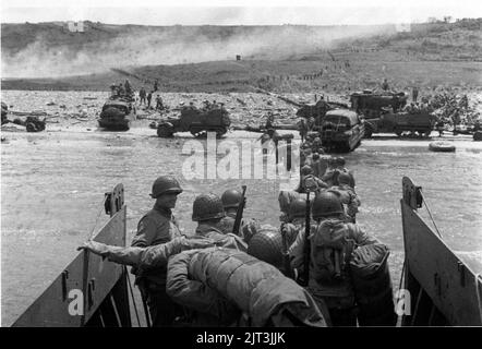 Troops wade ashore at Omaha Beach from a LCVP landing craft. Note DUKWs ...