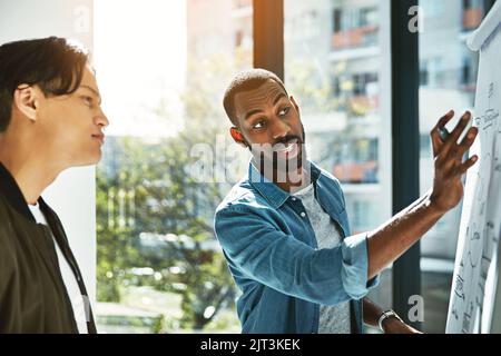 Making mind maps work for them. two young businessmen brainstorming with a whiteboard in the office. Stock Photo