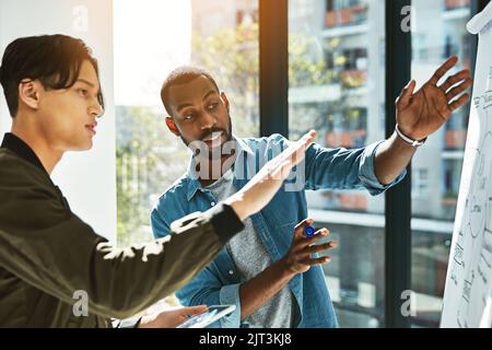 They love to bounce ideas off each other. two young businessmen brainstorming with a whiteboard in the office. Stock Photo