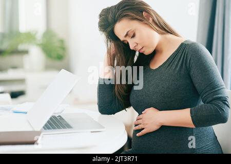 Suffering from a little morning sickness. a young pregnant woman feeling unwell while working from home. Stock Photo