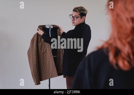 Man viewing a suit on a mannequin. Clothing designers working on a yellow jacket. Designer working on a bag that he shows to his clients. High quality photo Stock Photo