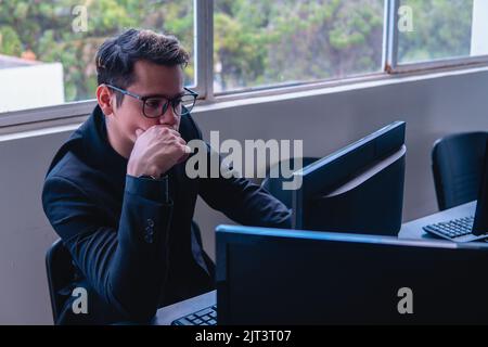 Man thinking in front of his computer monitor. Blond man working in the office. Business elegant man analyzing data on a computer. High quality photo Stock Photo